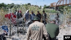 Migrantes venezolanos esperan a que la policía fronteriza de Estados Unidos corte el alambre que les impide El Paso luego de haber cruzado el Río Grande hacia Eagle Pass, Texas, el pasado 24 de septiembre. Las autoridades arrestaron a un presunto miembro de El Tren de Aragua.