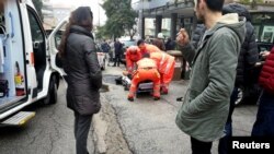 Healthcare personnel take care of an injured person after being shot by gun fire from a vehicle, in Macerata, Italy, Feb. 3, 2018. 