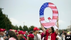 Demonstrant sa znakom Kju pred miting Donalda Trampa (Foto: AP/Matt Rourke)