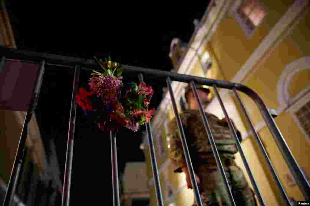 A military serviceman stands near flowers on a fence near the scene where a vehicle drove into a crowd during New Year's celebrations in New Orleans, Louisiana, Jan. 1, 2025.