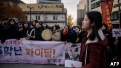 15일 서울에서 수험생이 수능 시험장에 들어가고 있는 가운데, 후배 학생들이 시험장 앞에서 응원구호를 외치고 있다. 