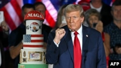 El expresidente de los Estados Unidos y candidato presidencial republicano, Donald Trump, gesticula junto a su pastel de cumpleaños, creado por el Club 47, durante un mitin de campaña mientras celebra su 78 cumpleaños en el Centro de Convenciones de West Palm Beach, Florida.