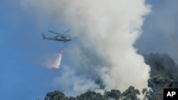 Un helicóptero rocía un incendio forestal en las montañas que dominan el este de Bogotá, Colombia, el lunes 22 de enero de 2024. 