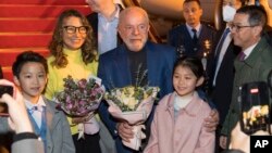 ARCHIVO - El presidente brasileño Luiz Inácio Lula da Silva y la primera dama Rosangela Silva reciben flores de parte de niños en una visita a China, el 12 de abril de 2023.