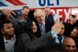 Britain's Prime Minister Boris Johnson has his picture taken with supporters prior to boarding his campaign bus, in Manchester, England, Nov. 15, 2019.