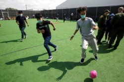 Niños migrantes juegan fútbol en un pequeño campo en el Centro de Detención del Departamento de Seguridad Nacional en Donna, Texas, el principal lugar de detención de niños no acompañados.
