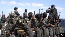 FILE - Armed fighters from the al-Shabab group travel on the back of pickup trucks outside Mogadishu in Somalia, Dec. 8, 2008. 