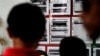 FILE - Migrants seeking asylum in the United States check their names on a printed list that's posted on a board near the international bridge, April 30, 2019, in Matamoros, Mexico.