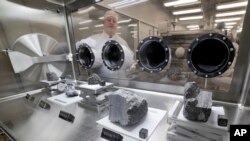 Ryan Zeigler, Apollo sample curator, left, stands next to a nitrogen-filled case displaying various lunar samples collected during Apollo missions, inside the lunar lab at the NASA Johnson Space Center, June 17, 2019, in Houston, Texas.