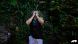  Una residente de una favela de Río de Janeiro, en Brasil, se refresca de un manantial natural durante una ola de calor extremo en la ciudad el 17 de noviembre de 2023. Archivo.