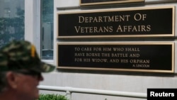 FILE - A man walks by the Department of Veteran Affairs building in Washington, May 23, 2014.