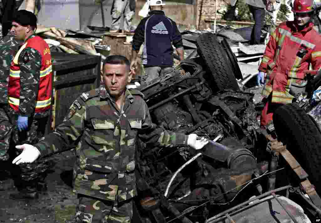 Lebanese army investigators gather next to burned and damaged cars at the site of explosions, in the suburb of Beir Hassan, Beirut, Lebanon, Feb. 19, 2014.