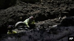 Socorristas trabajan en un vehículo que cayó en un socavón hace días, el jueves 29 de septiembre de 2022, en Villa Nueva, Guatemala. 
