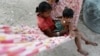 FILE - Children play in a hammock in Broma village in Kratie province, Cambodia, Oct. 22, 2012. 