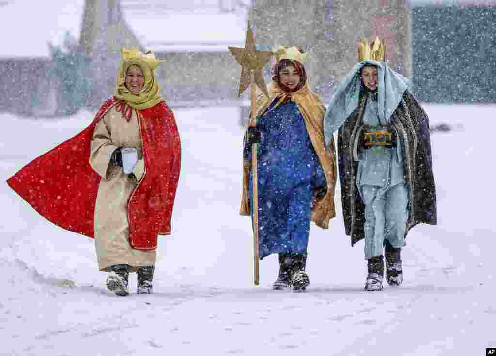 Miembros de un coro tradicional vestidos en el atuendo típico a través de la nieve en Eglingen, en el sur de Alemania, el sábado cinco de enero del 2019. 