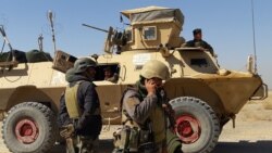 Afghan security forces stand near an armored vehicle during ongoing fighting between Afghan security forces and Taliban fighters in the Busharan area on the outskirts of Lashkar Gah, the capital city of Helmand province, May 5, 2021.