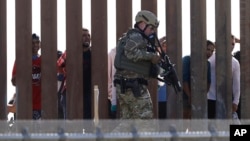 A U.S. Customs and Border Protection officer walks along a wall at the border between Mexico and the United States, as seen from San Diego, California, Nov. 25, 2018.