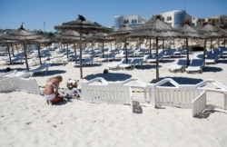 FILE - A young woman lays a flowers at the scene of a shooting in Sousse, Tunisia, June 27, 2015.
