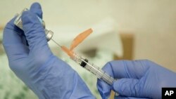 FILE - A nurse practitioner prepares a flu vaccination in Rockville, Maryland, Aug. 27, 2010. A puzzling study of U.S. pregnancies suggests that women who received back-to-back flu shots between 2010 and 2012 - after a new swine flu vaccine came out - more often had miscarriages. 