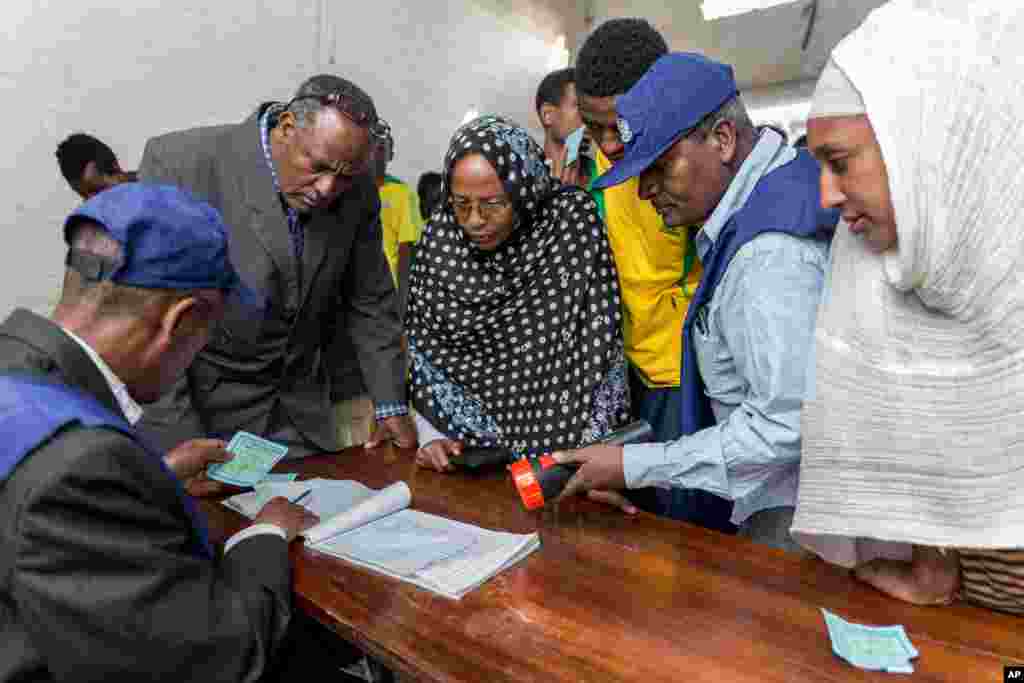 Election officials verify voters' cards as people wait to vote in general election, in Addis Ababa, May 24, 2015.