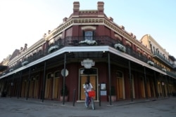 FILE - A man rides his bicycle in front of a boarded up French Quarter restaurant amid the outbreak of the coronavirus, in New Orleans, Louisiana, March 25, 2020.