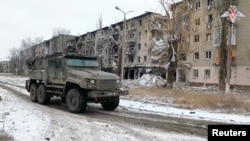 Un vehículo militar ruso pasa junto a edificios residenciales dañados durante el conflicto entre Rusia y Ucrania en la ciudad de Avdiivka en la región de Donetsk, Ucrania controlada por Rusia, en esta imagen tomada de un video publicado el 20 de febrero de 2024.