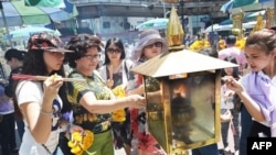 ស្រ្តី​អុជធូប​មុន​ពេល​ធ្វើ​ការ​បួងសួង​នៅ​កន្លែង​សក្ការបួូជា Erawan ដែល​ជា​កន្លែង​ទេសចរណ៍​ប្រកបដោយ​ប្រជាប្រិយភាព​មួយ ទី​ដែល​មនុស្ស​២០នាក់​ត្រូវ​បាន​សម្លាប់​ដោយ​ការ​បំផ្ទុះ​គ្រាប់បែក​។