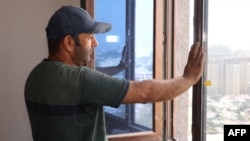 Tajik construction worker Zoir Kurbanov looks out from a window as he renovates a new apartment in Dushanbe on Sept. 17, 2023.