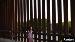 Una pequeña, que forma parte de un grupo de migrantes llegados de Centroamérica, camina junto a la valla fronteriza que separa EE. UU. y México, tras entrar al país de manera irregular, el 6 de abril de 2019.