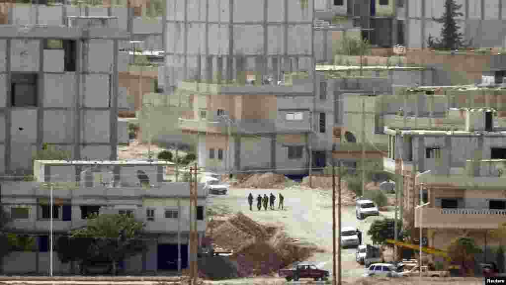 Unidentified people walk through the Syrian town of Kobani, near the Turkish-Syrian border, Oct. 15, 2014.