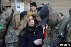 Žena se obraća borcu Hajat Tahrir al-Šama (HTS) tokom, kako je HTS saopštio, bezbednosnih provera kako bi se pronašli "ostaci" snaga svrgnutog sirijskog predsednika Bašara el Asada, u naselju Vadi al-Dahab u Homsu, Sirija, 2. januara 2025. REUTERS/Khalil Ashavi