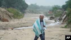Un hombre camina sobre el barro causado por el huracán Norma en San José del Cabo, México, el sábado 21 de octubre de 2023. Norma se debilitó y fue degradado a Categoría 1 en la escala de vientos de huracanes.