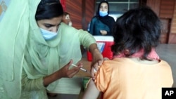 FILE - A woman receives the Pfizer COVID-19 vaccine from a health worker at a vaccination center in Islamabad, Pakistan, Oct. 4, 2021.