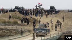 Iraqi security forces gather near a temporary bridge built by the corps of engineers in the Iraqi army south of Ramadi, during a visit by Iraqi Prime Minister Haider al-Abadi on Dec. 29, 2015, after government forces recaptured the city from the Islamic State jihadist group.