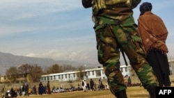 FILE - Taliban security personnel keep watch ahead of the court flogging of women and men at a football stadium in Charikar city of Parwan province, Dec. 8, 2022. 