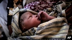 A newborn baby girl lays in her mothers' arms right after being born onboard a Spanish rescue vessel on the Mediterranean Sea, Sept. 6, 2017. A rescued woman from Ghana has given birth to a girl immediately after being rescued while trying to cross the Mediterranean Sea from Libya to Italy. 