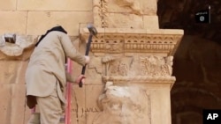 Gambar yang diambil dari sebuah video yang dipasang pada tanggal 3 April 2015, di sebuah website yang sering digunakan oleh ISIS menunjukkan searing militan menghancurkan dinding di kota tua Irak, Hatra.