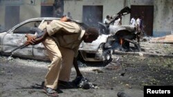 FILE - A Somali policeman collects unexploded ordnance in Somalia's capital Mogadishu, Feb. 15, 2010. A girl died and at least 17 people were injured Saturday in Somalia's Sool region when an unexploded grenade she was playing with went off.