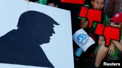 FILE - People hold banners as they protest next to the Brandenburg Gate, beside the U.S. embassy, against the U.S. withdrawal from the Paris climate change deal, in Berlin, Germany, June 2, 2017.