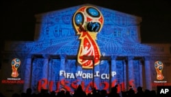 FILE - Journalists look at a light installation showing the official logotype of the 2018 FIFA World Cup during its unveiling ceremony at the Bolshoi Theater building in Moscow, Oct. 28, 2014. 