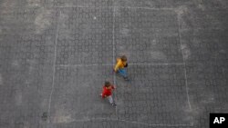 Ukrainian refugee children walk along the backyard of the Lauder Morasha Jewish school in Warsaw, Poland, Thursday, July 28, 2022. (AP Photo/Michal Dyjuk)