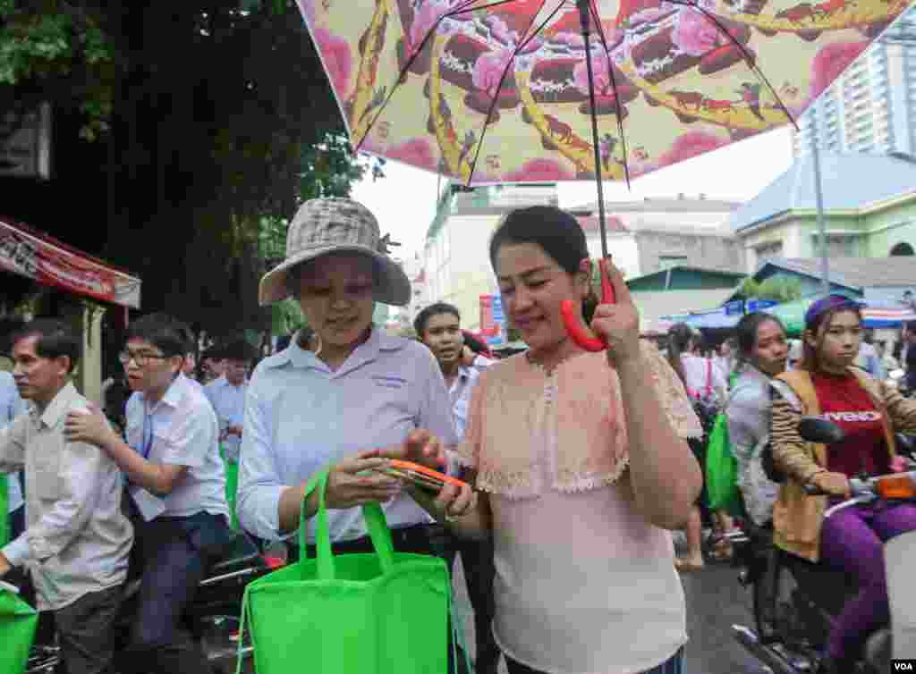 ម្ដាយបាំងឆ័ត្រឲ្យកូនស្រីដែលទើបតែចេញពីបន្ទប់ប្រឡងនៅថ្ងៃបញ្ចប់នៅវិទ្យាល័យព្រះយុគន្ធ នៅថ្ងៃអង្គារ ទី២៣ ខែសីហា ឆ្នាំ២០១៦ នៅរាជធានីភ្នំពេញ។ (ឡេង ឡែន/VOA)