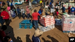Des personnes touchées par le ralentissement économique du au coronavirus reçoivent des dons de nourriture dans le quartier d'Iterileng près de Laudium, au sud-ouest de Pretoria, Afrique du Sud, le 20 mai 2020.