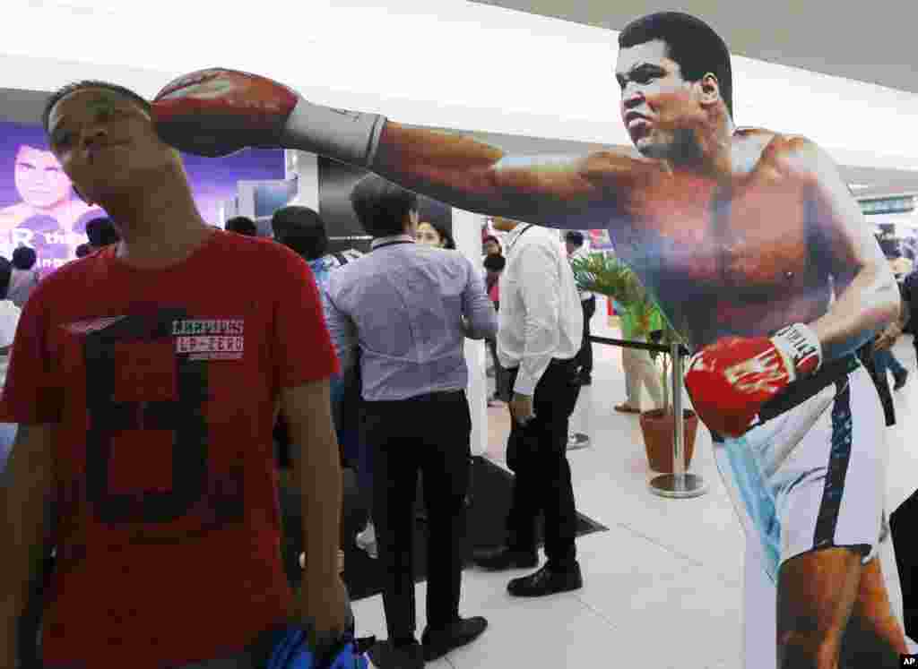 A Filipino fan poses before a standee of Muhammad Ali at an exhibit of photos and memorabilia launched last week to pay tribute to Muhammad Ali, in Quezon city, Philippines, June 10, 2016.