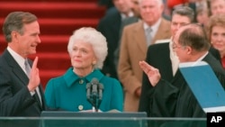 En esta foto del 20 de enero de 1989, George H.W. Bush jura al cargo como presidente número 41 de Estados Unidos ante el presidente de la Corte Suprema, William Rehnquist, mientras la primera dama Barbara Bush sostiene la Biblia.
