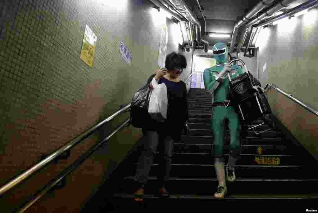Tadahiro Kanemasu alias '"Superhero pembantu pengangkut barang" membawa keranjang belanja seorang ibu di sebuah stasiun di Tokyo, Jepang. Mengenakan pakaian hijau ketat dengan aksen perak dan topeng yang sesuai, sang "superhero" menunggu di tangga stasiun kereta bawah tanah Tokyo, untuk membantu para penumpang yang lanjut usia, membawakan barang-barang yang berat atau membantu para ibu dengan kereta bayi.