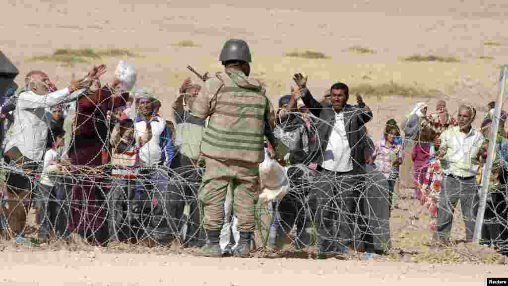 A Turkish soldier stands guard as Syrian Kurds wait behind the border fence to cross into Turkey near the southeastern town of Suruc in Sanliurfa province, Sept. 19, 2014.