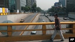 A man walks over what would usually be a very busy thoroughfare in Mexico City, April 6, 2016. City authorities barred millions of vehicles from the streets due to a pollution alert. (AP Photo/Dario Lopez-Mills)