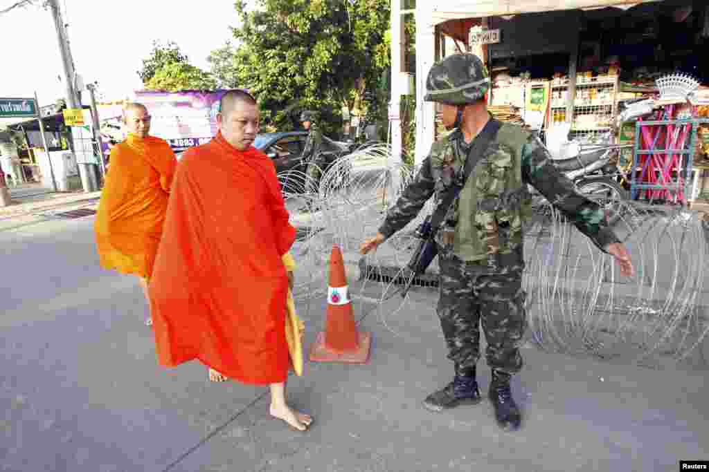 Barefoot Buddhist monks walk past a checkpoint near a pro-government &quot;red shirt&quot; supporter encampment in Nakhon Pathom province, on the outskirts of Bangkok, May 22, 2014.