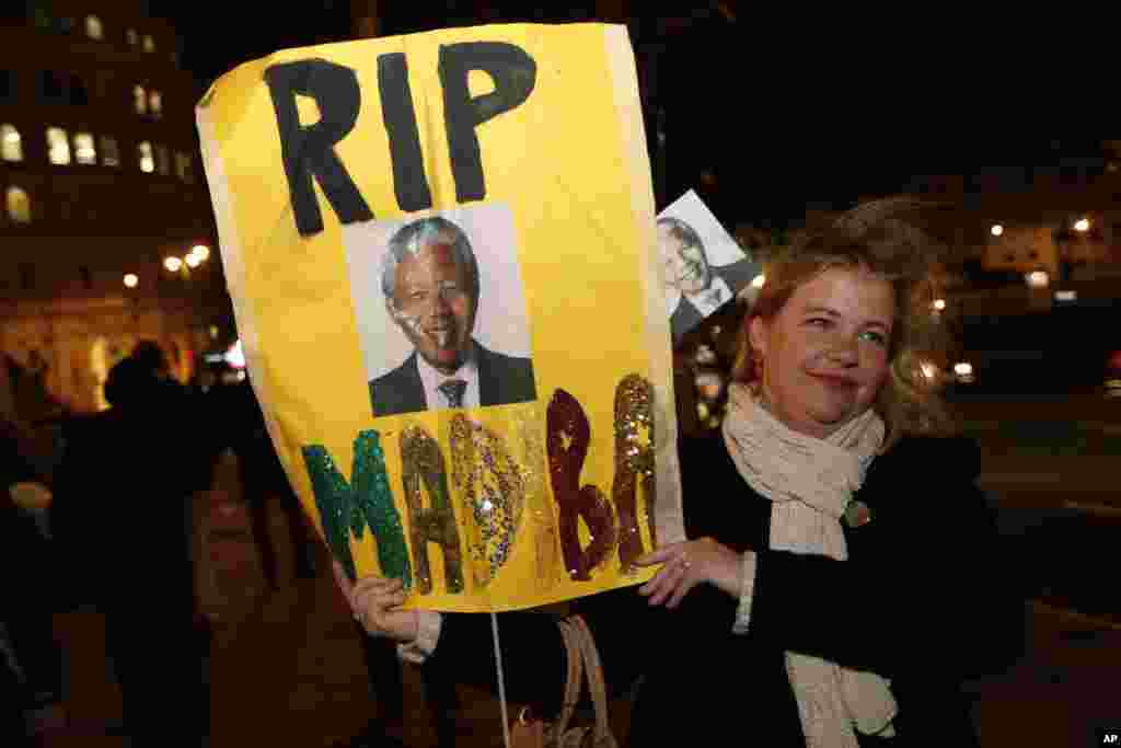 A woman with a banner pays tribute to Nelson Mandela outside the South African High Commission in London, Dec. 6, 2013.
